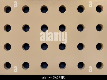 Close up of hole perforated panel in gold beige paint finish. Seamless background texture. Stock Photo