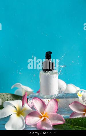 Delicate drops of water splash around a moisturizing serum alongside elegant plumeria blooms. Stock Photo