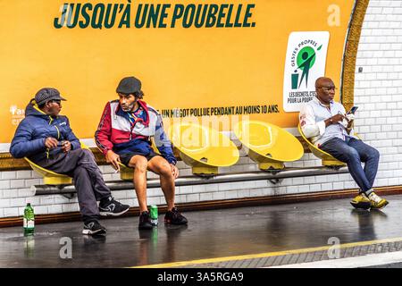 Three men, two talking and smoking, sitting on seats in the Metro underground transport system, Paris. Stock Photo