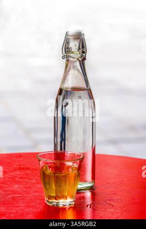 Bottle of water and small glass of beer on round red table, Brussels, Belgium. Stock Photo