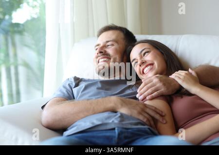 Happy couple at home relaxing looking away sitting on a couch at home Stock Photo