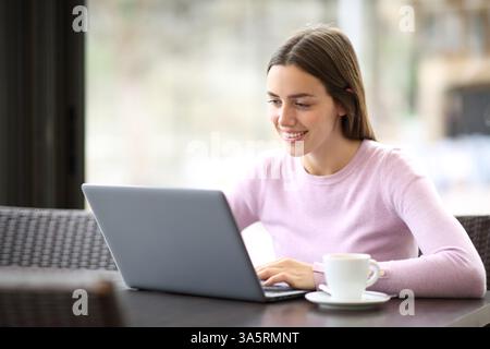 Happy woman using laptop sitting in a coffee shop interior Stock Photo