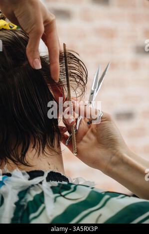 A professional barber using scissors and a comb to cut a client's hair, showcasing precision Stock Photo