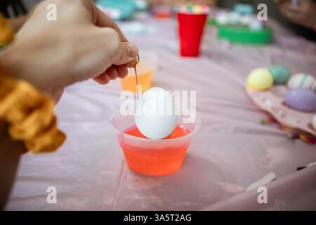 Close up of hand dipping egg into egg dye for Easter Stock Photo