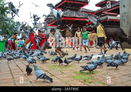 Kathmandu, Nepal - September 18: Nepalese kids celebrating the Haritalika Teej festival and playing with pigeons on Durbar square near Royal Palace on Stock Photo