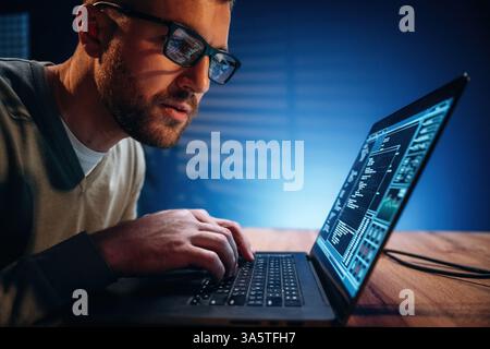 Focused on job. Male programmer is working indoors by a laptop. Stock Photo