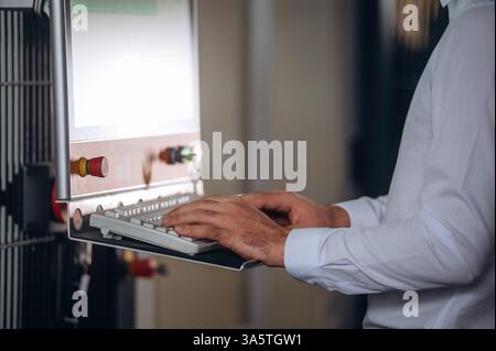 Typing on the keyboard. Close up view of man that is working in the modern factory. Stock Photo