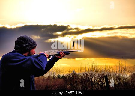 Shotgun shooting as the sun goes down with sunbeams and  shells ejecting from the Hatsun 12 gauge Stock Photo