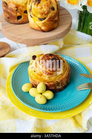 Delightful Easter sweet bread,  a traditional treat,  is presented on a vibrant blue plate, adorned with pastel yellow eggs. Perfect for spring celebr Stock Photo