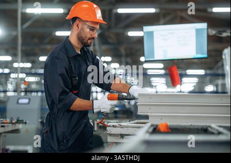 Using screwdriver. Man is working in the modern factory. Stock Photo