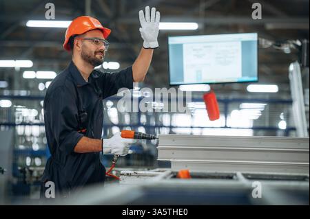 Using screwdriver. Man is working in the modern factory. Stock Photo