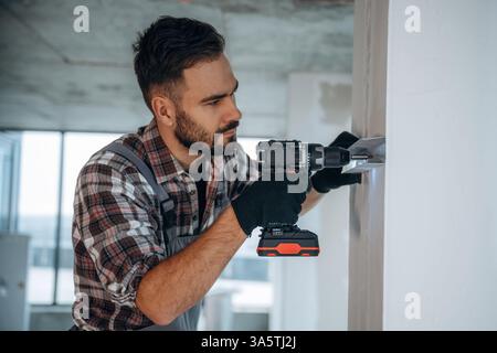 Using the drill. A man is renovating an unfinished room. Stock Photo