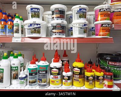 Variety of adhesives and sealants on store shelf with labels and prices. Stock Photo