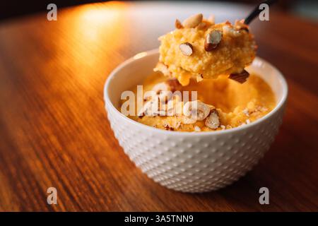 corn porridge with nuts on spoon in a white bowl. Stock Photo