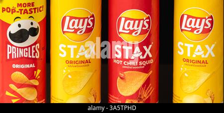 Close up of Various Pringles Potato Chip on market shelves. Colorful cans of Pringles and Lay's Stax potato chips on a supermarket shelf, offering a w Stock Photo