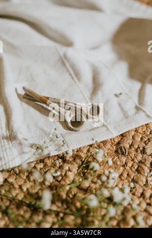 Two small white spoons are on a white cloth. The cloth is on a carpet. The spoons are placed on the cloth in a way that they look like they are holdin Stock Photo