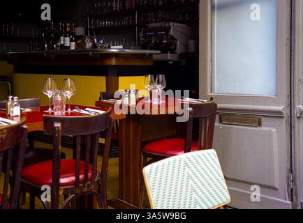 An empty outdoor cafe table with glasses and cutlery, set against a backdrop of a restaurant interior. Rustic charm, European setting Stock Photo