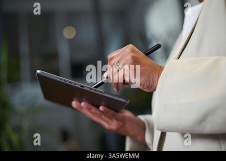 Close-Up of a Hand Using a Stylus on a Tablet in a Modern Office Stock Photo