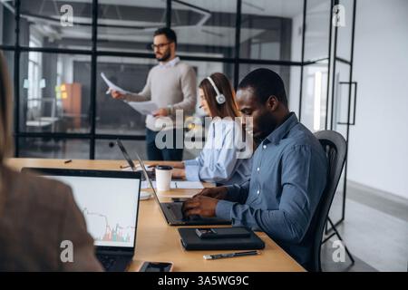 Wireless devices, laptops on the table. Professional workers are in the modern office together. Stock Photo