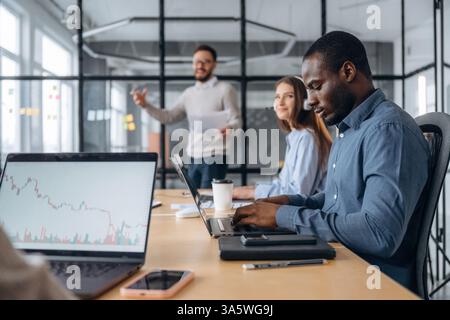 Focused, sitting by laptop. Professional workers are in the modern office together. Stock Photo