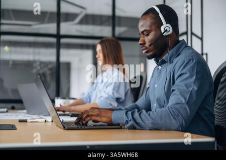 In headphones and with laptops. People are working in the call center. Stock Photo