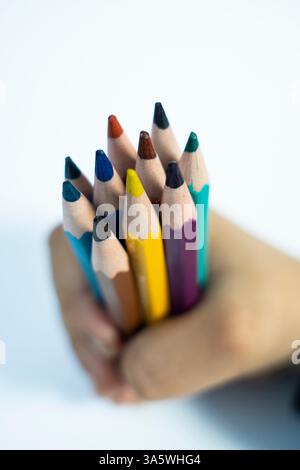 A joyful photo of kid holding colorful pencils, showcasing creativity and learning on a white background. Perfect for educational and parenting conten Stock Photo