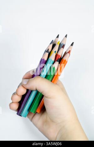 A joyful photo of kid holding colorful pencils in her hand, showcasing creativity and learning on a white background. Perfect for educational and pare Stock Photo