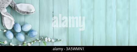 Cute Easter bunny ears with naturally dyed eggs and spring flowers. Holiday background. Table top view. Stock Photo