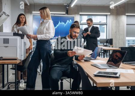 Using printer. Group of office workers are indoors together. Stock Photo
