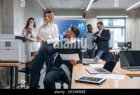 Using printer. Group of office workers are indoors together. Stock Photo