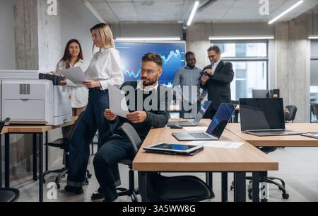 Using printer. Group of office workers are indoors together. Stock Photo