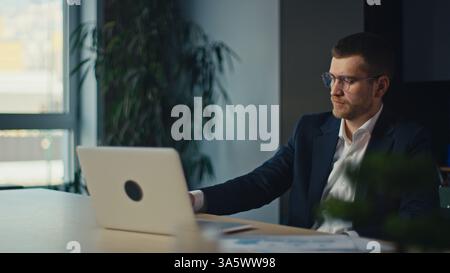 Focused business consultant engaged in a corporate meeting, attentively listening while working on a laptop in a modern office. Concept of leadership Stock Photo