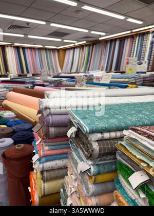 Rolls and stacks of colorful fabrics at Mustafa Centre. Located in Singapore, it is a popular 24-hour shopping destination. Stock Photo