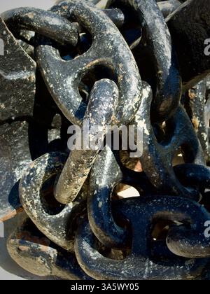 Detailed shot of large rusty metallic chains with textured surfaces under sunlight, symbolizing strength, industry, and reliability. Stock Photo
