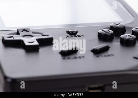 A stylized black retro handheld gaming console with classic buttons, isolated against white. This compact device evokes nostalgic gaming memories and Stock Photo
