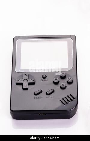 A stylized black retro handheld gaming console with classic buttons, isolated against white. This compact device evokes nostalgic gaming memories and Stock Photo