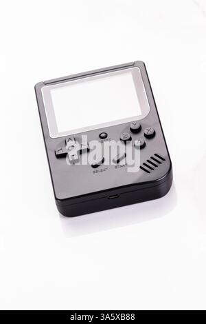 A stylized black retro handheld gaming console with classic buttons, isolated against white. This compact device evokes nostalgic gaming memories and Stock Photo
