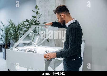 Standing, working. Man is in the office with 3d printer. Stock Photo