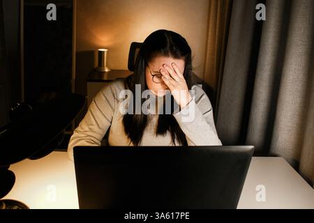 Tired woman working on computer touching her head because of headache. Office worker with migraine. Stressed overworked employee suffering from pain o Stock Photo