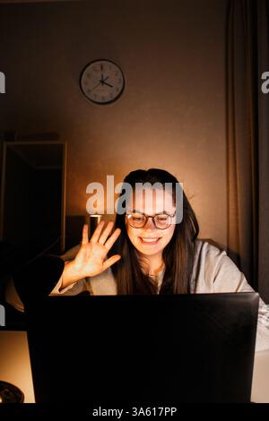 Cheerful millennial woman enjoy videocall with friends using laptop. Gesturing and smiling. Talking with friends who living far. Cherishing long dista Stock Photo