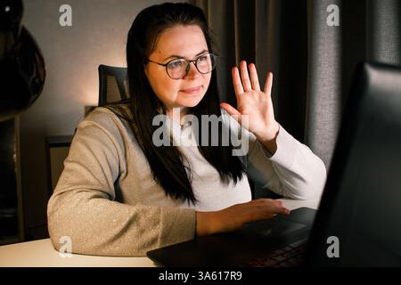 Smiling friendly female freelancer having online conference call with client sitting at home. Remote job concept Stock Photo