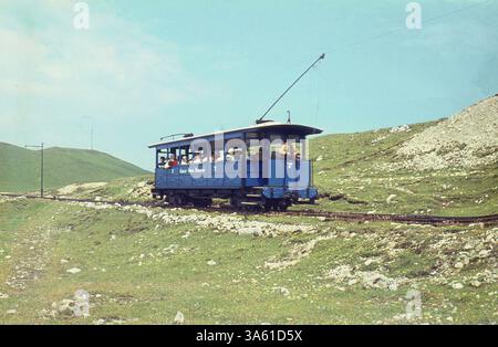 1970s, picture shows people travelling on a cable or tramcar of The Great Orme Tramway. First opened in 1902, Britain's only funicular, or cable-hauled tramway that travels on public roads, starts at Victoria Station, Llandudno, North Wales before entering the Great Orme country park and going up to the summit of the mountain. Stock Photo