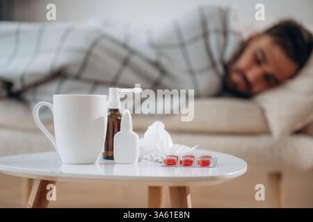 Water, spray and pills on the table. Sick man is feeling bad at home. Stock Photo