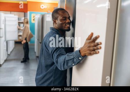 Man with woman are choosing fridge in the shop. Stock Photo