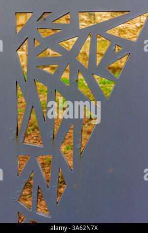 Geometric Metal Gate Panel with Abstract Cutouts in Outdoor Environment Stock Photo