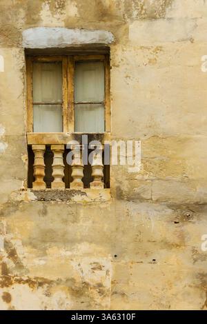 Weathered Building Facade with Rustic Window and Ornate Stucco Details Stock Photo