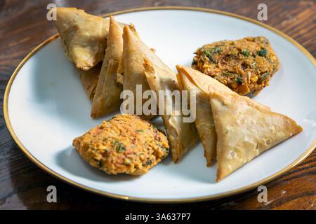 A group of Indian tea-time snacks, including samosa and vada, on a plate. Stock Photo