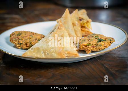 A group of Indian tea-time snacks, including samosa and vada, on a plate. Stock Photo