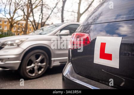 UK- Learner driver L plates attached to car on urban road in the UK Stock Photo