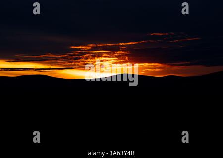 Fiery Sunset: Red Sun Setting Behind the Horizon with Dramatic Cloudscape Stock Photo